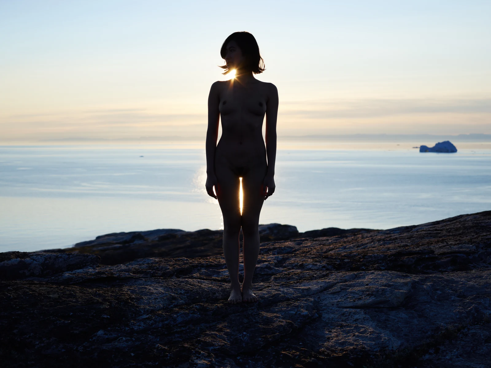 A standing silhouette against the sea and a low Greenland sun.